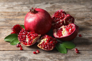 Depositphotos 245796140 S 300x200 - Ripe pomegranates and leaves on wooden background